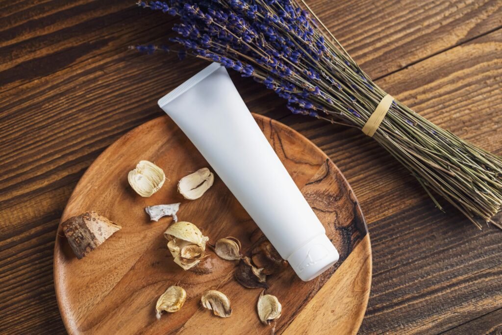 A cosmetic tube on a wooden plate with dried lavender and petals, perfect for natural skincare themes.