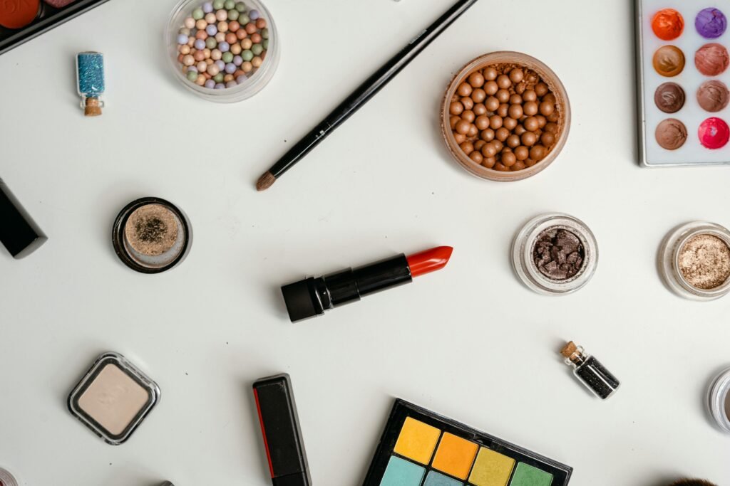 A stylish flat lay of diverse cosmetic products, including eyeshadows and lipstick, on a white background.