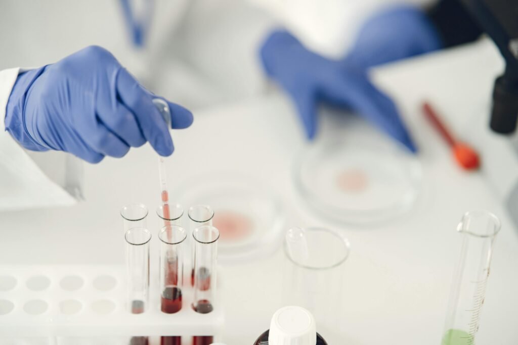 A scientist using pipette for chemical analysis in a laboratory with test tubes and protective gloves.