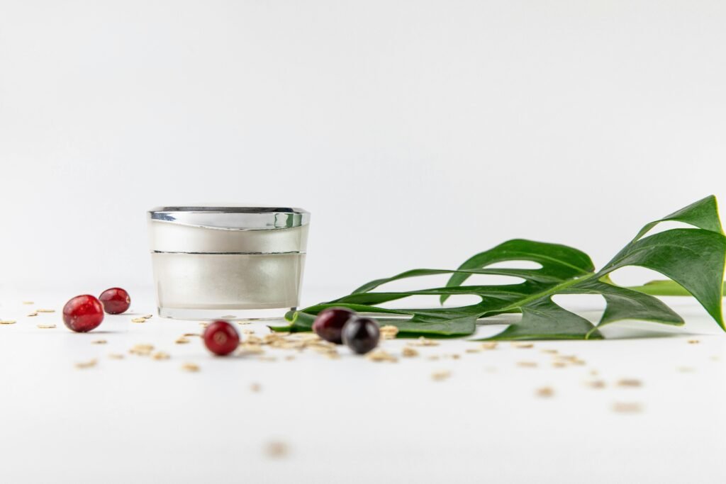 Close-up of a cosmetic cream jar with natural elements like leaves and berries on a white background.